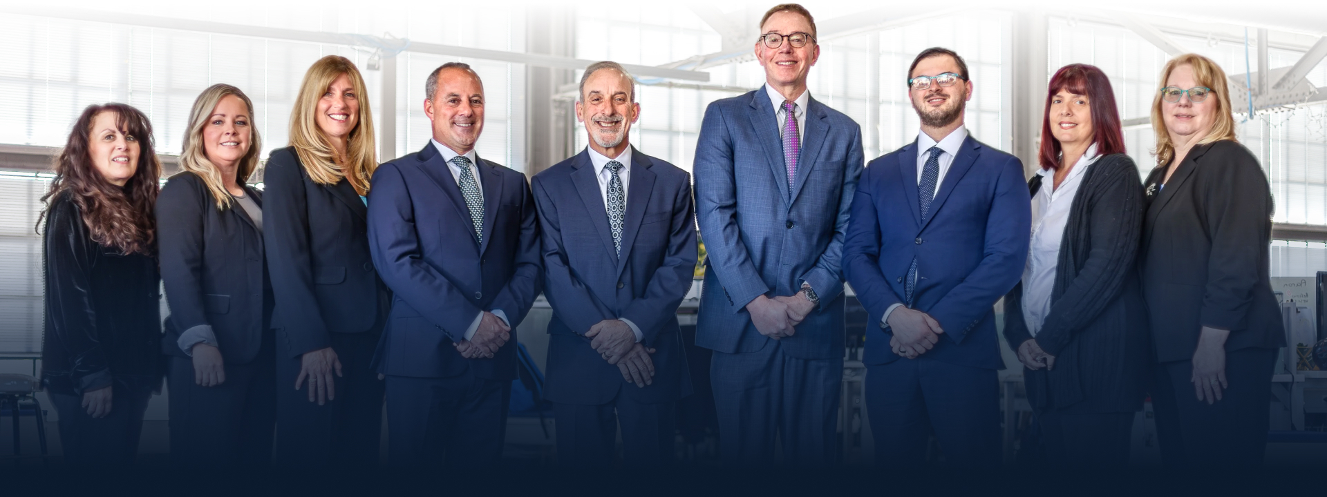 The RMS Law legal team standing together in a bright, modern office space.